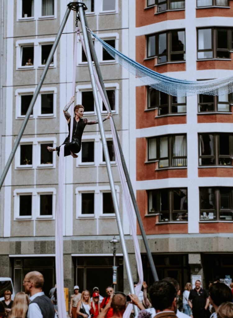 Luftartistin am hellen Vertikaltuch über dem Publikum bei Ein Mosaik der Farben in Leipzig